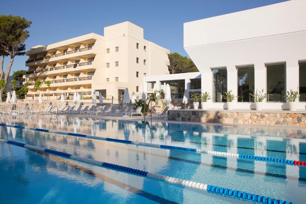 a swimming pool in front of a hotel at Hotel Bella Playa & Spa in Cala Ratjada