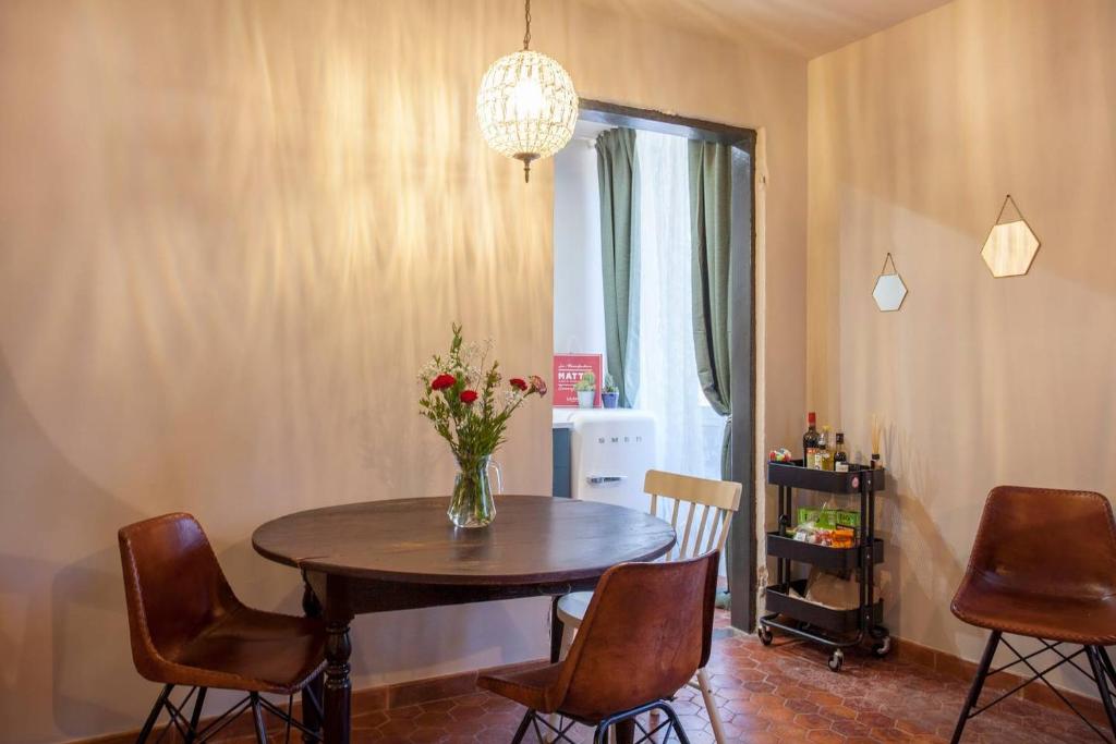 una mesa de comedor con sillas y un jarrón de flores. en CASA VECCHIA centre historique, en Bastia