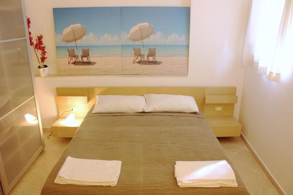 Un dormitorio con una cama con sillas y una pintura en Exclusive Marina Apartment, en Castellammare del Golfo