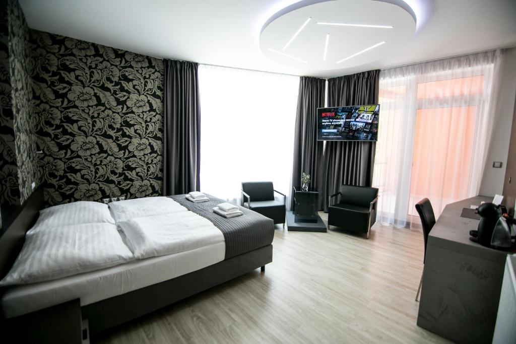 a bedroom with a bed and a desk and a television at Hotel U Kostela in Modřice