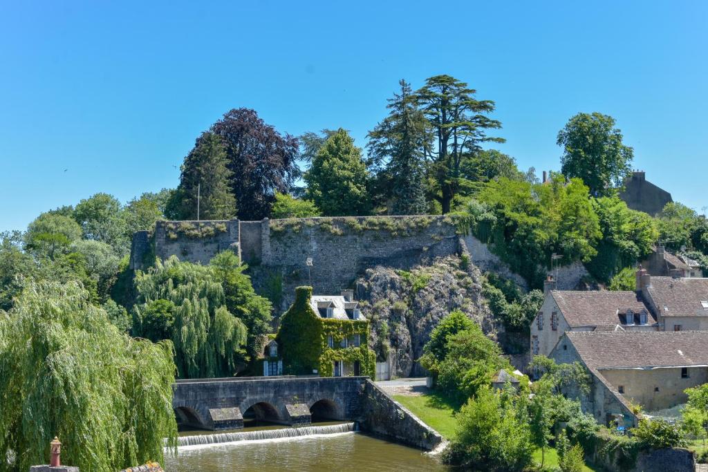 un antiguo castillo con un puente sobre un río en Le refuge des Alpes Mancelles en Fresnay-sur-Sarthe