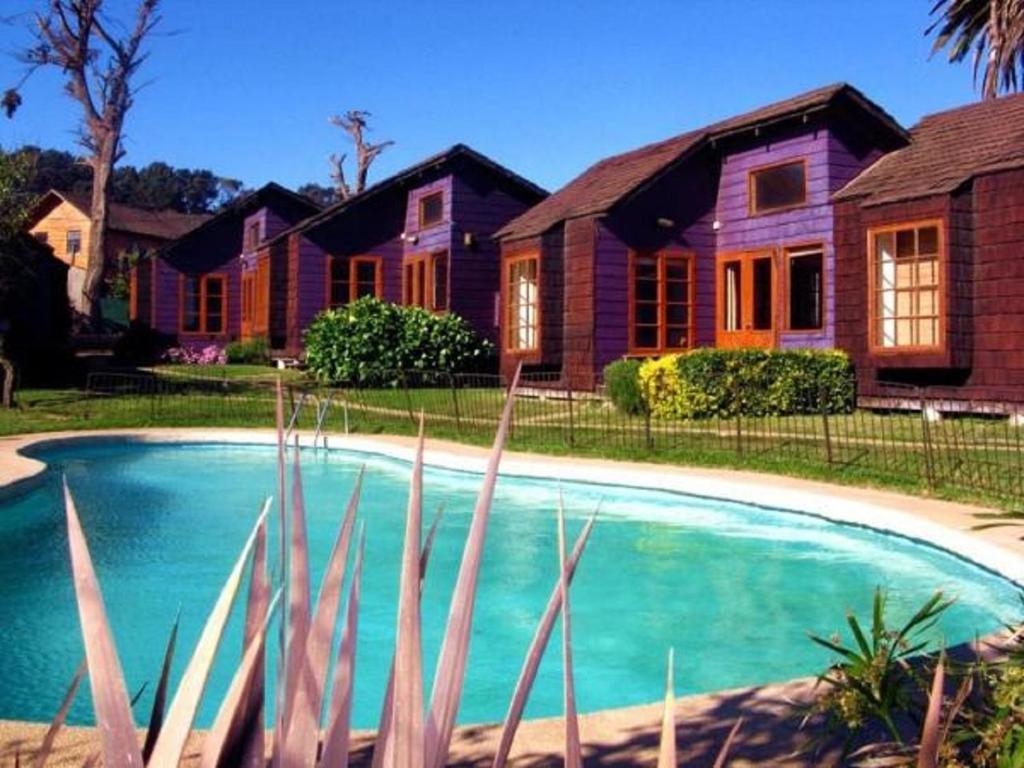 une maison avec une piscine en face d'une maison dans l'établissement Cabañas, Habitaciones y Restaurant Montemar, à El Tabo