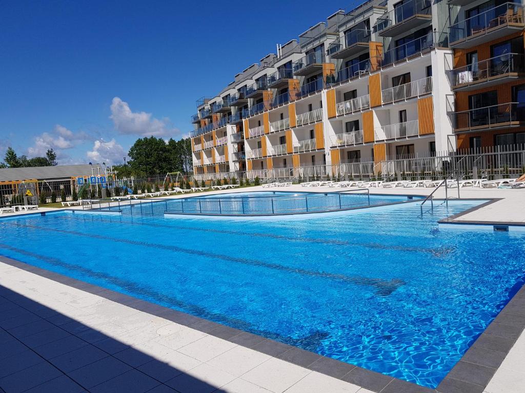 a large swimming pool in front of a building at Apartament SOLEIL Kołobrzeg in Kołobrzeg