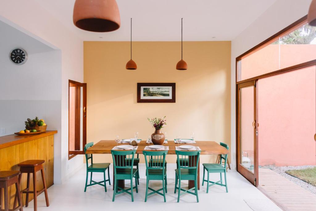 a dining room with a wooden table and green chairs at Casa Crescente in Trancoso