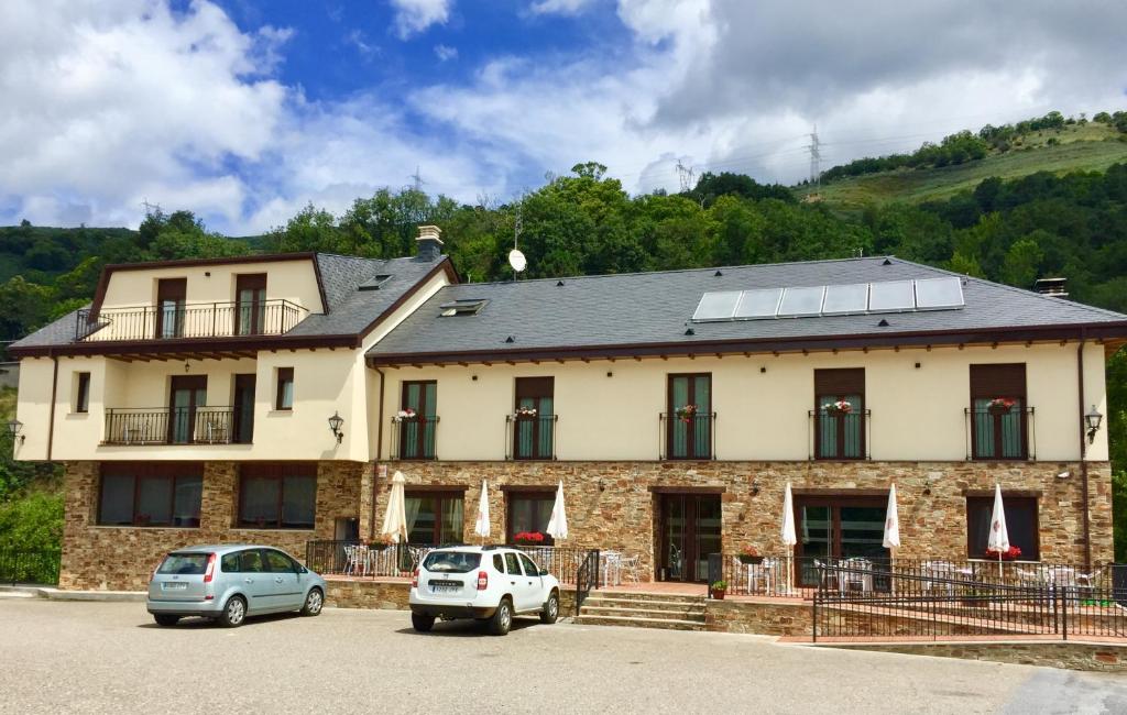 un edificio con dos coches estacionados frente a él en Hotel Rural Nova Ruta, en Trabadelo