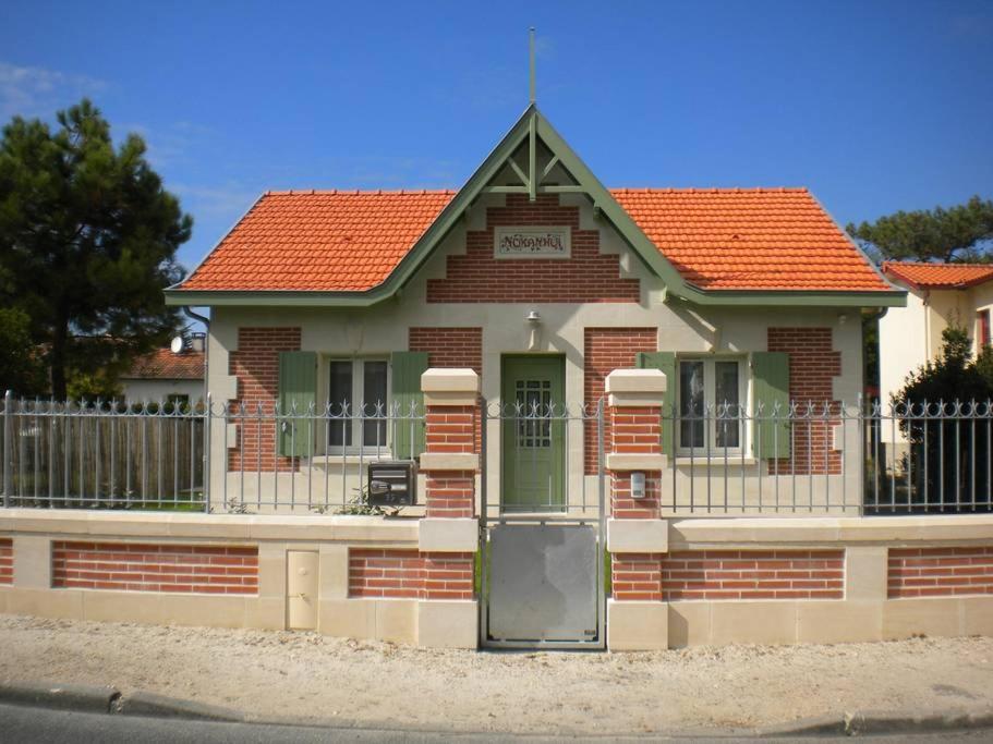 uma casa de tijolos com um telhado vermelho e uma porta em Nokanhui em Soulac-sur-Mer