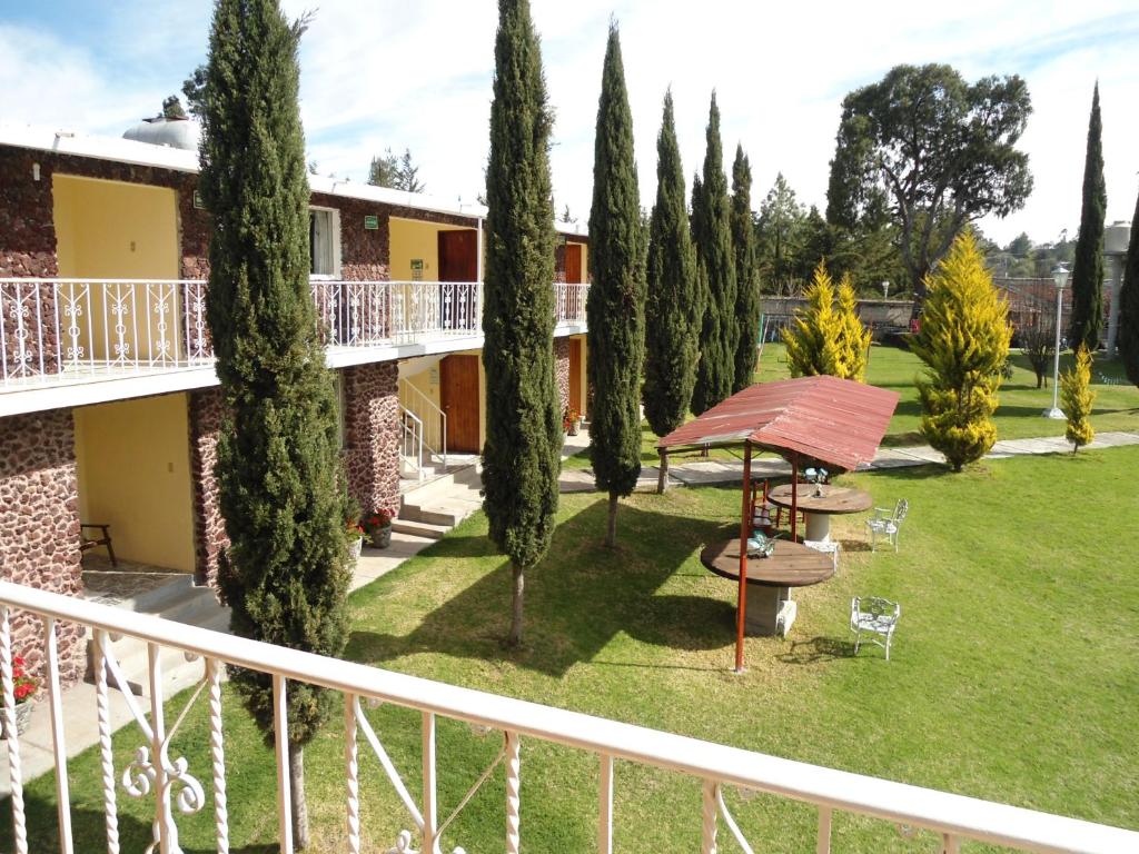 a balcony of a building with a yard with trees at Posada Dos Hermanos in Huasca de Ocampo