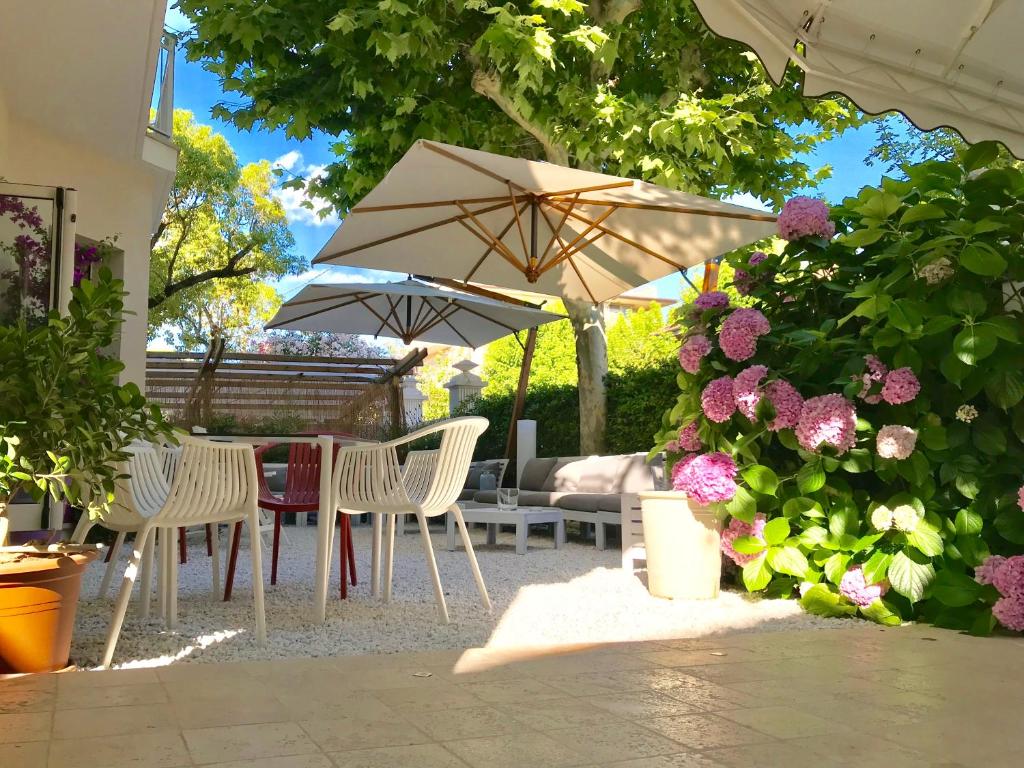 a patio with chairs and an umbrella and flowers at Petit Hotel in Lido di Camaiore