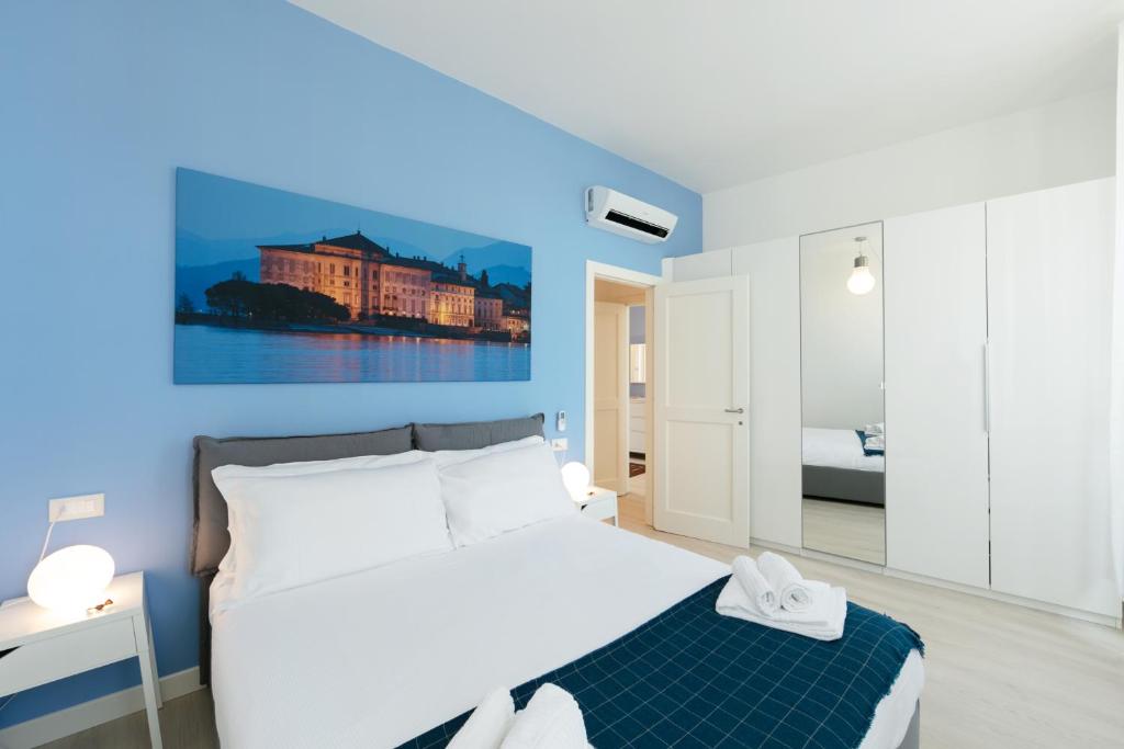 a bedroom with a white bed and a blue wall at Verbania - Luxury Italy Apartments in Verbania