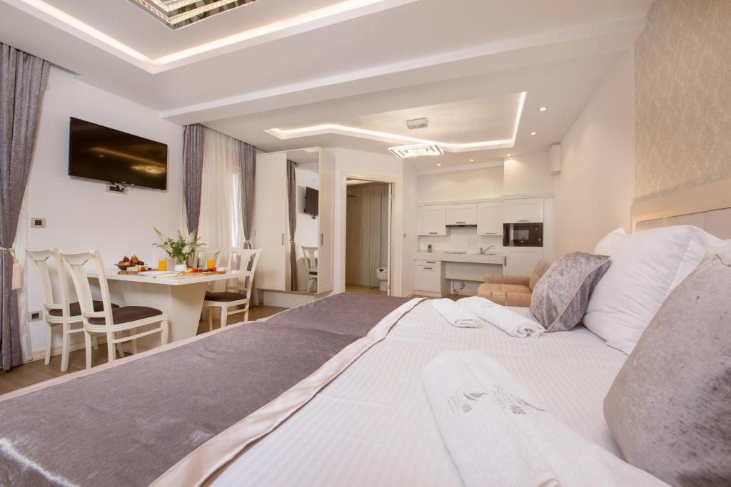 a bedroom with a large white bed and a kitchen at Splendido MB Apartments in Tivat