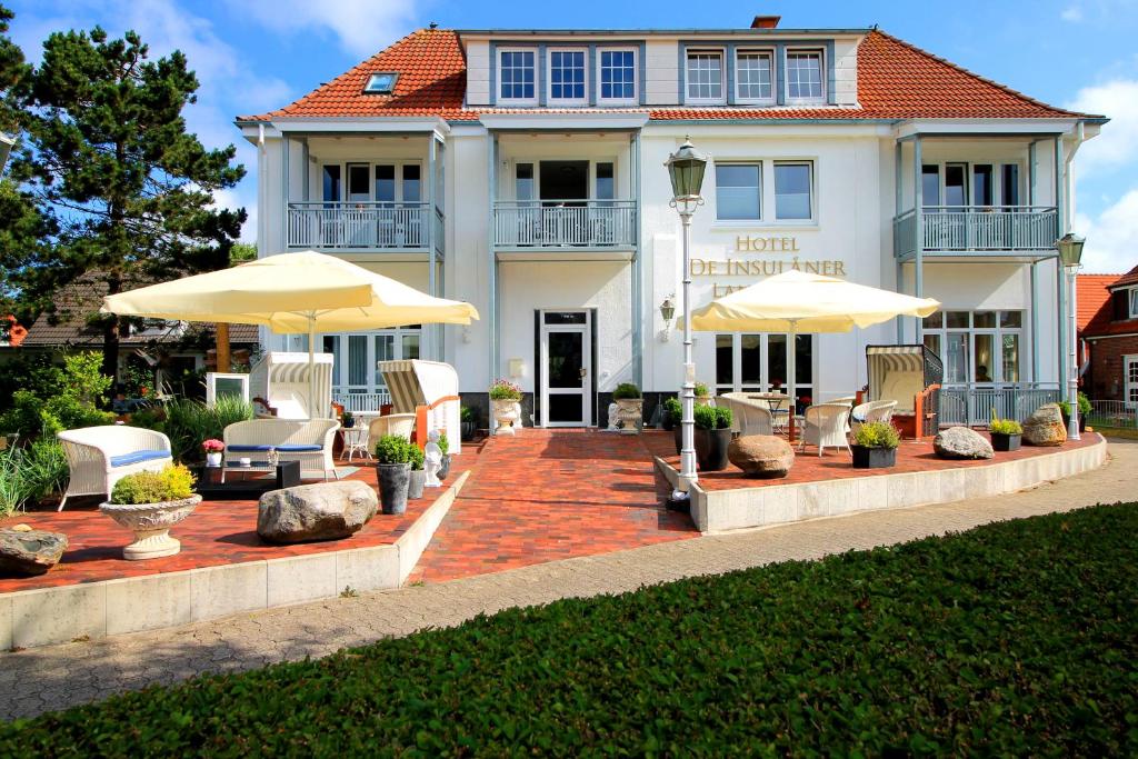 a house with umbrellas and chairs in front of it at Hotel De Insulåner in Langeoog