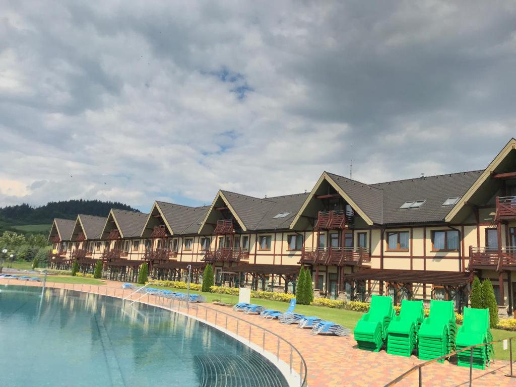 a resort with a swimming pool and green chairs at Apartmány Thermal in Bešeňová