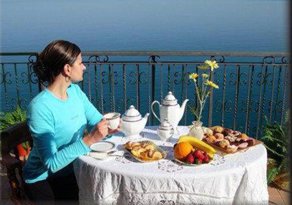 Una donna seduta a un tavolo con un piatto di cibo di B&B Casa Armonia a Pizzo