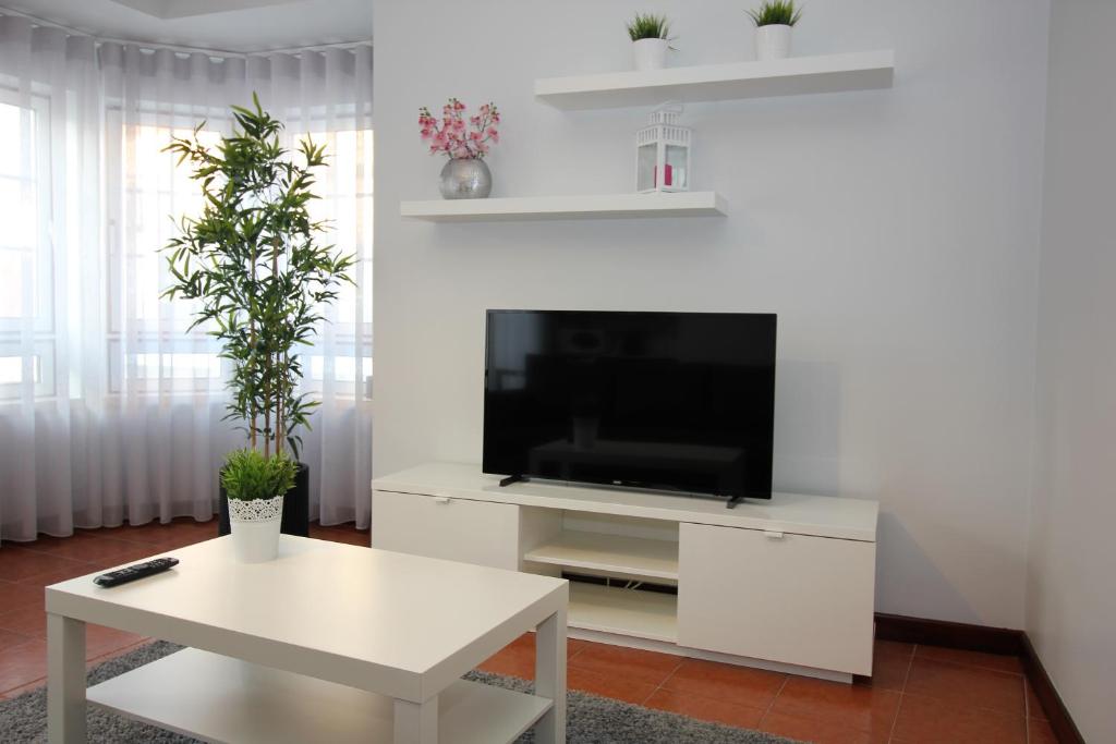 a living room with a tv and a white table at Subvilla Beach Place in Nazaré