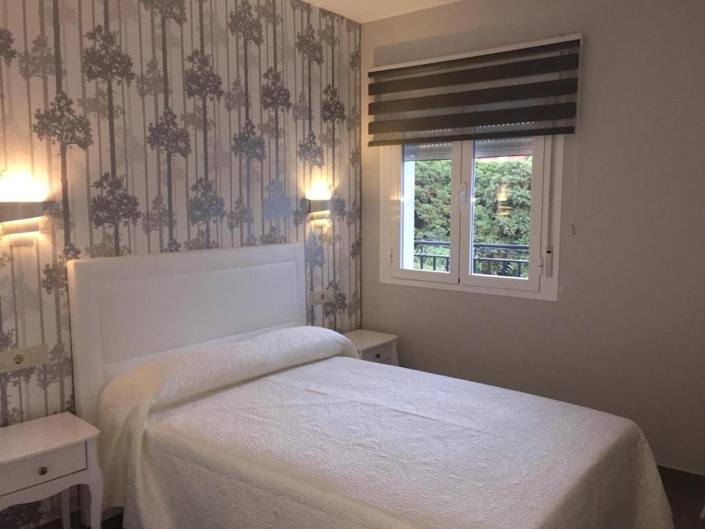 a bedroom with a white bed and a window at Apartamento San Miguel N.3 in Jarandilla de la Vera
