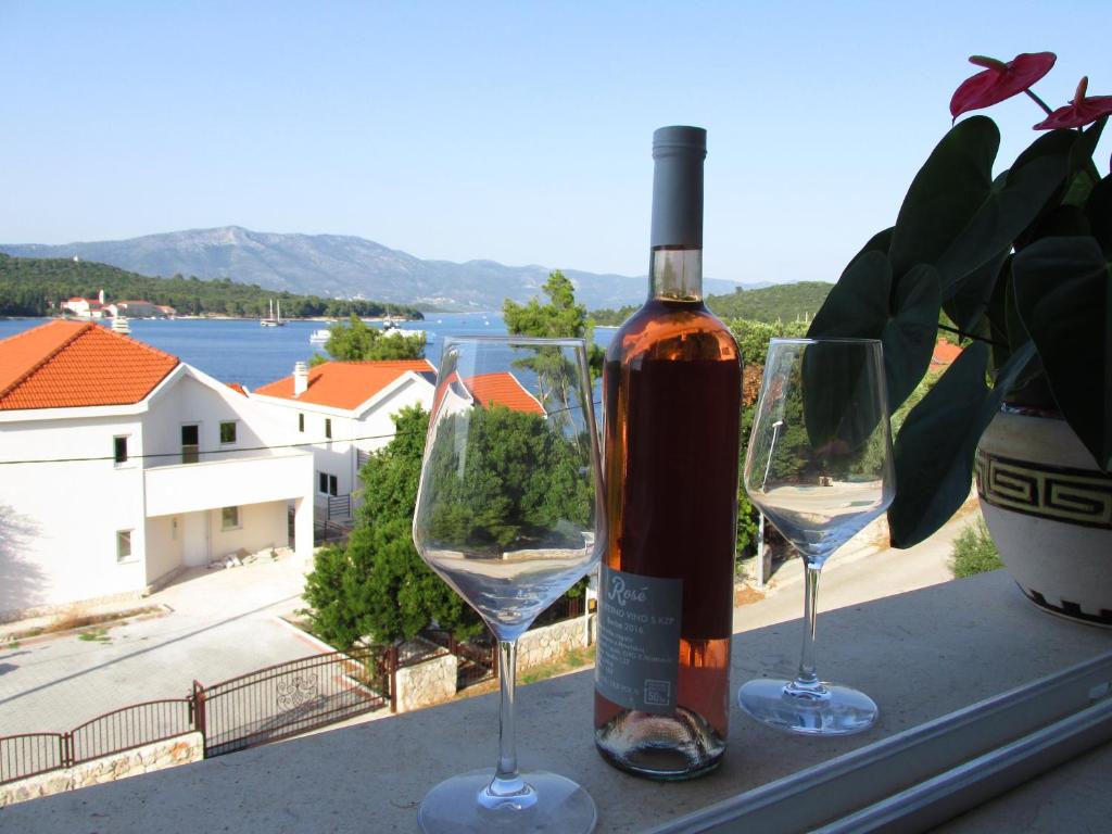 una botella de vino y dos copas de vino en una ventana en APARTMANI "ZUKA", en Korčula