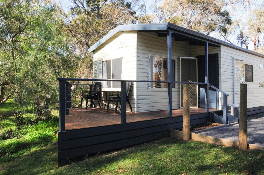 uma pequena cabina branca com um deque com uma mesa em Euroa Caravan Park em Euroa