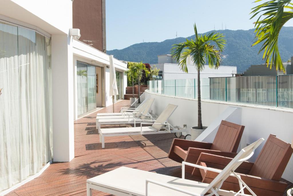 Un balcón con sillas y mesas en un edificio en Ipanema Design with brand new pool ilive002, en Río de Janeiro