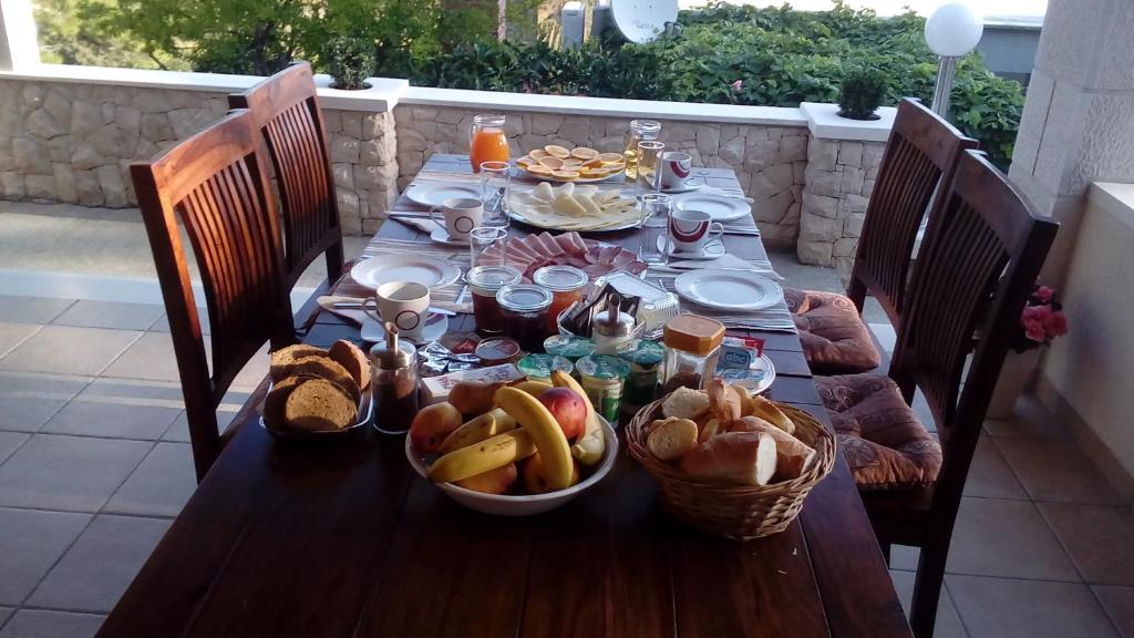 a wooden table with food and baskets of bread at VILLA Apartments Mate Cebalo in Lumbarda