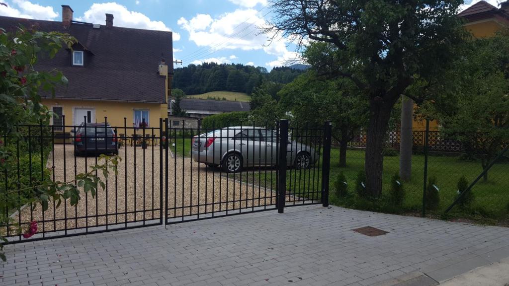 a fence with a car parked in front of a house at Apartmá Andělka in Lipova Lazne