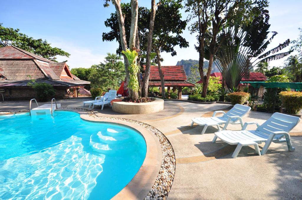Railay Viewpoint Resort في شاطئ رايلي: مسبح مع كراسي جلوس بجانب بيت