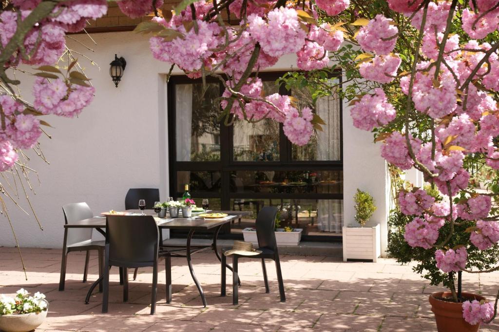 una mesa y sillas sentadas bajo flores rosas en Les Chambres de La Maxe, en La Maxe