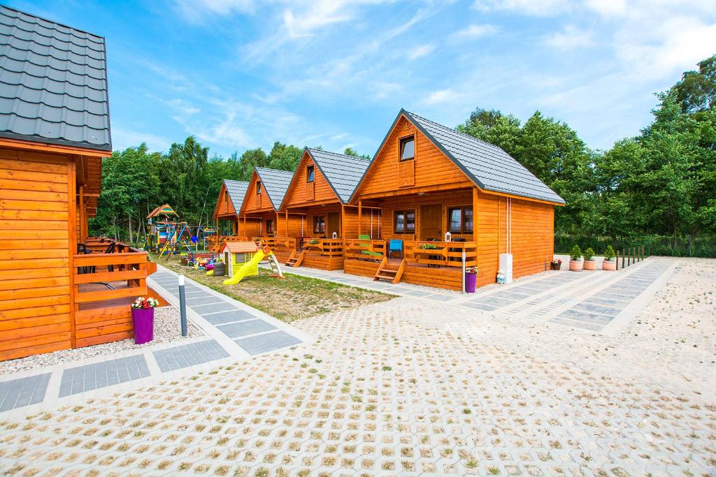 a row of wooden cabins with a playground at Domki KARO in Rowy