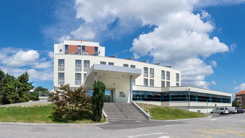 um edifício branco com escadas em frente a um parque de estacionamento em Hotel Park em Čakovec