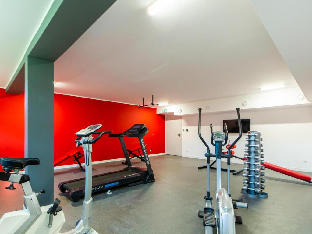a gym with two tread machines and a red wall at Apartamenty Baltia Kołobrzeg - Bliżej Morza in Kołobrzeg