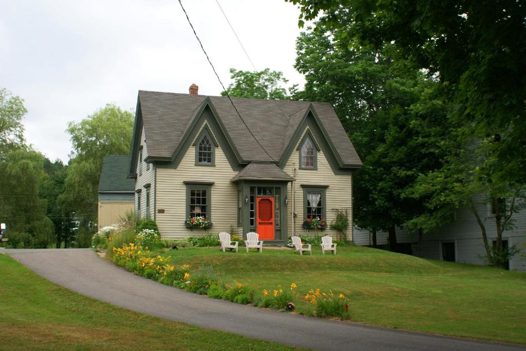 a house with a red door and chairs in the yard at Fisherman's Daughter B&B in Mahone Bay