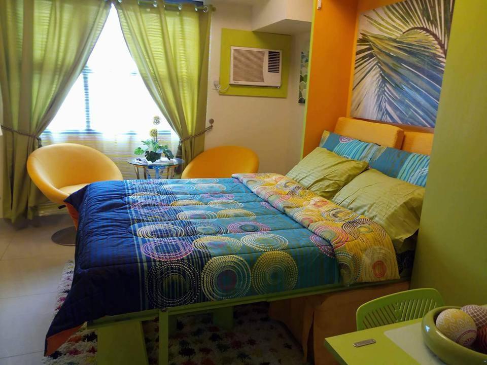 Nica's Place Property Management Services at Horizons 101 Condominium في مدينة سيبو: غرفة نوم مع سرير ولحاف ملون