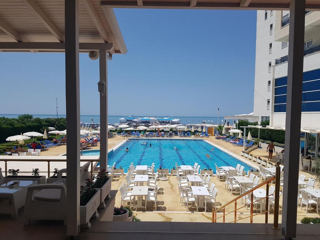 a swimming pool with chairs and tables and a building at Duplex in Durrës