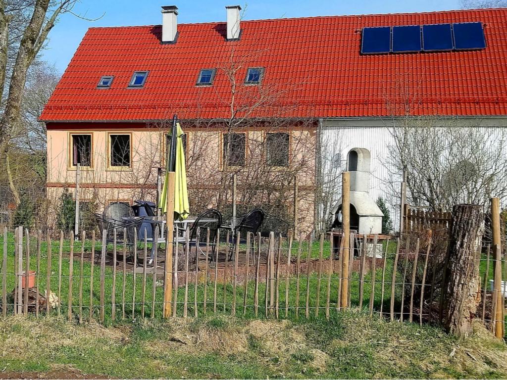 a house with a red roof is behind a fence at Pleasant Apartment in Kierspe with Private Terrace in Kierspe