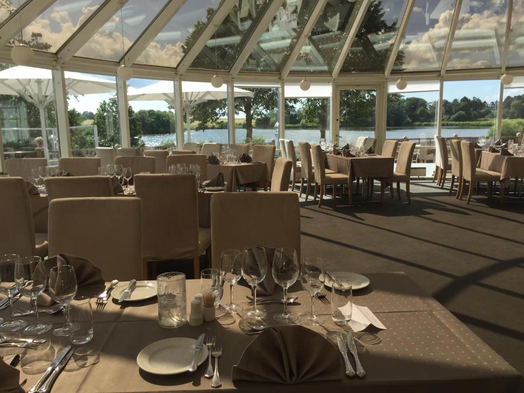 un ristorante con tavoli e sedie con bicchieri da vino di Hotel Sørup Herregaard a Ringsted