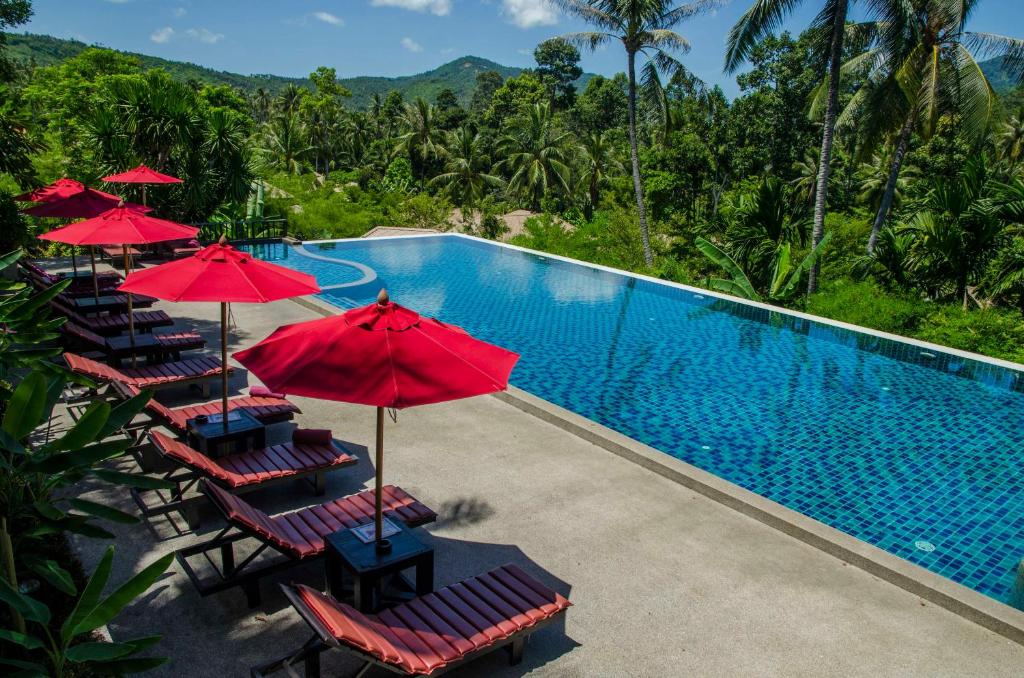 - une piscine avec des chaises longues et des parasols à côté d'un complexe dans l'établissement Kirikayan Residences Koh Samui, à Mae Nam Beach