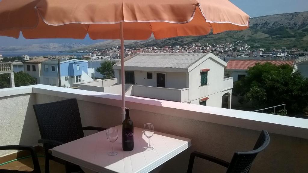 uma mesa com dois copos de vinho e um guarda-chuva em Apartment Edina Pag em Pag