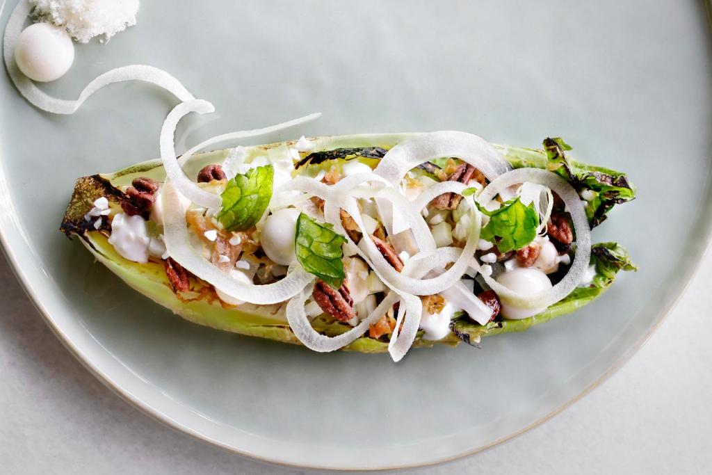 a sandwich with onions and greens on a plate at The Principal Madrid, Small Luxury Hotels in Madrid