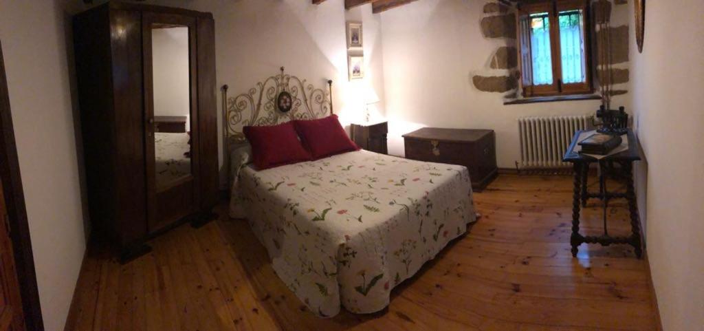 Un dormitorio con una cama con almohadas rojas. en La Casa del Valle, en Ailanes