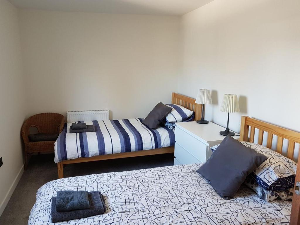 Un dormitorio con 2 camas y una silla. en Stornoway Lido flats, en Stornoway