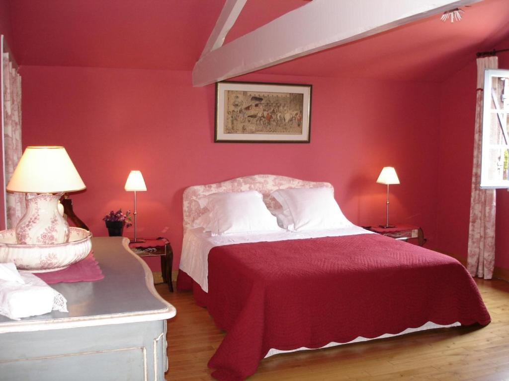 um quarto vermelho com uma cama com uma parede vermelha em La Petite Provence de Touron em Pujols Gironde