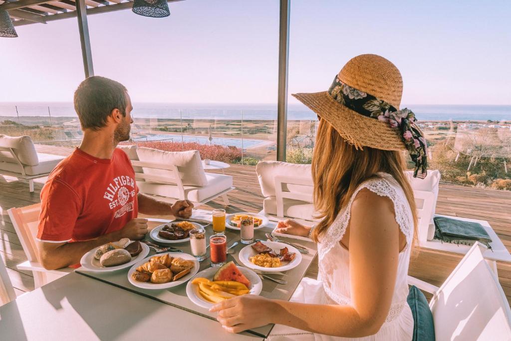 a man and a woman sitting at a table with food at Palmares Beach House Hotel - Adults Only in Lagos