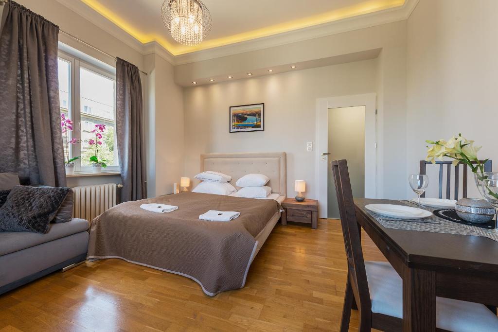 ein Schlafzimmer mit einem Bett, einem Tisch und einem Sofa in der Unterkunft P&O Apartments Andersa INTRACO in Warschau