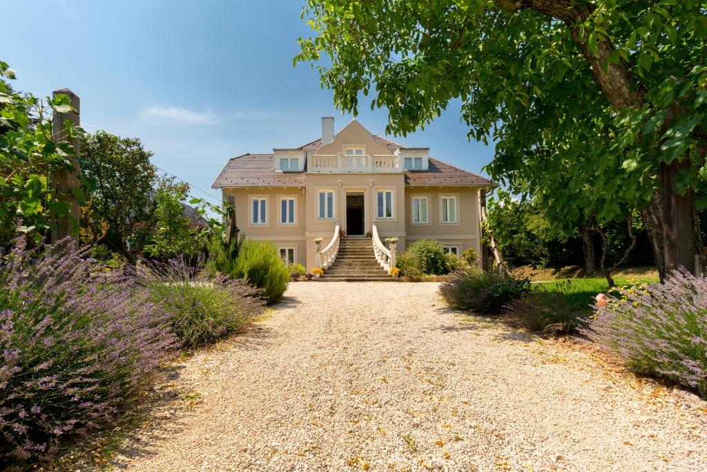 a large house with a gravel driveway at Manor House Inn Csopak in Csopak