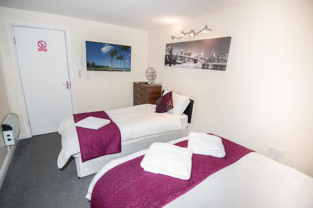ブラッドフォードにあるBradford serviced apartmentsの小さな部屋のベッド2台 紫の毛布付