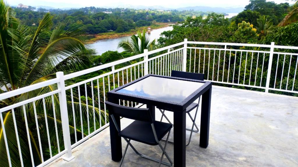 a black table and chair on a balcony overlooking a river at Mahaweli View Inn in Kandy