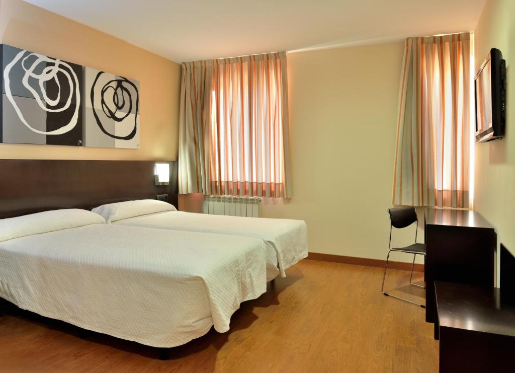 a bedroom with a large white bed and a desk at Hotel El Paso Honroso in Hospital de Órbigo