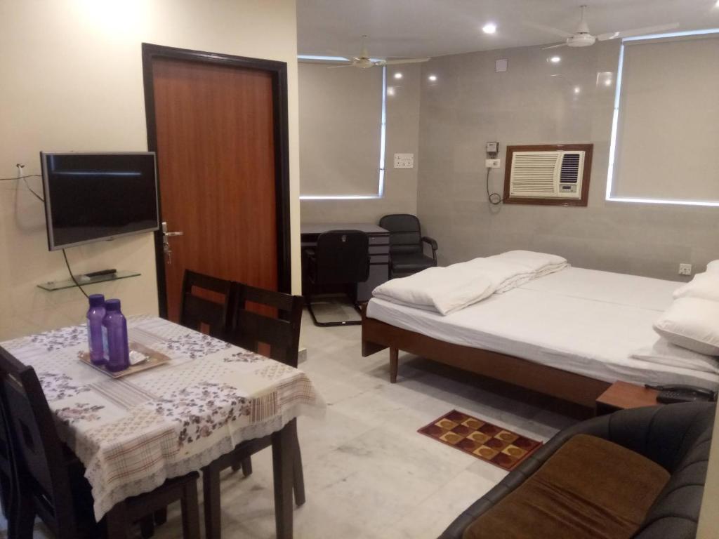 a room with two beds and a table and a tv at Service Apartments, Park Street, Calcutta in Kolkata