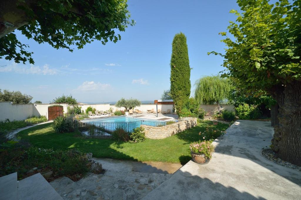 un cortile con piscina e un albero di Le Mas Des Sorcières - Maison d'hôtes a Valréas