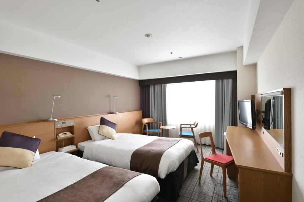 una camera d'albergo con due letti e una televisione di Hotel Granvia Hiroshima a Hiroshima