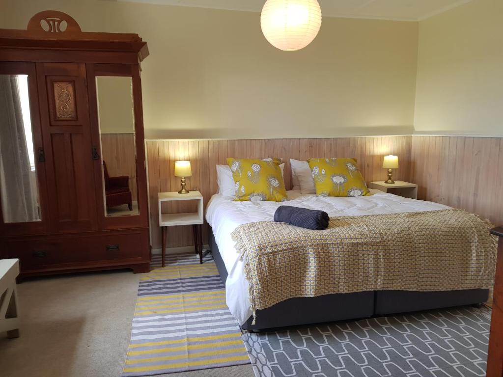 a bedroom with a large bed with yellow pillows at Settler Cottage Apartment in Grahamstown